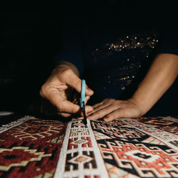 Cutting ethnic carpet with scissors. High quality photo